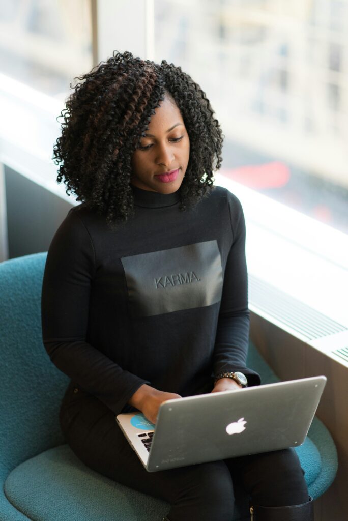 Confident woman using a laptop in a bright office environment, symbolizing modern professional life.